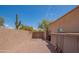 View of a gravel backyard with wood gate, stucco walls, desert plants and blue sky at 4706 E Rancho Caliente Dr, Cave Creek, AZ 85331