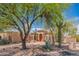 Attractive single-story home showcasing desert landscaping, including mature trees and a wooden front door at 4706 E Rancho Caliente Dr, Cave Creek, AZ 85331