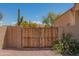 Wooden privacy gate set in a stucco wall, with native vegetation and pink flowering bushes at 4706 E Rancho Caliente Dr, Cave Creek, AZ 85331