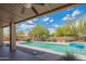 Covered patio view of backyard pool and spa with desert landscaping and clear blue sky at 4706 E Rancho Caliente Dr, Cave Creek, AZ 85331