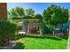 Lush backyard featuring a covered patio with a dining set, mature trees, and well-maintained lawn at 512 W Roma Ave, Phoenix, AZ 85013