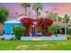 Charming blue home with vibrant bougainvillea, a well-manicured lawn, and lovely palm trees at 512 W Roma Ave, Phoenix, AZ 85013