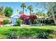 Charming blue home with vibrant pink bougainvillea and lush green lawn and mature palm trees at 512 W Roma Ave, Phoenix, AZ 85013
