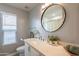 Bright bathroom featuring a large, round mirror, modern vanity, and natural light from a window with blinds at 5831 W Saragosa St, Chandler, AZ 85226
