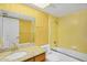 Bathroom with a yellow tiled shower-tub combo, vanity, and vintage wallpaper, creating a bright, retro aesthetic at 6011 N 2Nd St, Phoenix, AZ 85012