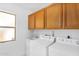 Bright laundry room with a utility sink, wood cabinets, and white washer and dryer at 6011 N 2Nd St, Phoenix, AZ 85012