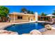 Inviting pool area with rock features, lush landscaping, and a covered patio, perfect for enjoying sunny days at 6533 E Kelton Ln, Scottsdale, AZ 85254