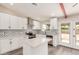 A modern kitchen boasts white cabinets, an island, stainless steel appliances, and a tiled backsplash at 655 E Hondo Ave, Apache Junction, AZ 85119