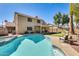 Spacious backyard featuring a pool, covered patio, artificial turf, mature trees, and desert landscaping at 6938 W Wescott Dr, Glendale, AZ 85308