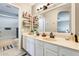 Bright bathroom featuring double sinks, white cabinets, a large mirror, and convenient wall shelving at 6938 W Wescott Dr, Glendale, AZ 85308