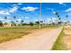 Expansive community featuring mature palm trees, grassy area, and walking path under a bright, partly cloudy sky at 7302 E Baseline Rd, Mesa, AZ 85209