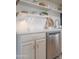 Close-up of a modern kitchen with stainless steel appliances, white cabinetry and open shelving at 7802 E Kimsey Ln, Scottsdale, AZ 85257