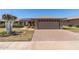 Well-maintained single-story home with a brick driveway, desert landscaping, and a two-car garage at 10449 W Tropicana Cir, Sun City, AZ 85351