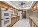 Cozy kitchen featuring wooden cabinetry, white appliances, and tile flooring for a classic, functional design at 10449 W Tropicana Cir, Sun City, AZ 85351