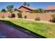 Fenced backyard with green lawn, bordered by red brick walkway and mature landscaping at 11664 W Eagle Ct, Surprise, AZ 85378