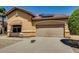Tan home features a two-car garage, awning over a window, desert landscaping and solar panels at 11664 W Eagle Ct, Surprise, AZ 85378