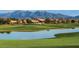 Picturesque view of the golf course with a pond and mountain backdrop at 14878 W Verde Ln, Goodyear, AZ 85395
