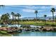 Scenic view of a lush golf course with a beautiful water feature and palm trees at 14878 W Verde Ln, Goodyear, AZ 85395