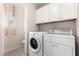 Well-lit laundry room equipped with a washer, dryer, and overhead storage cabinets at 16036 N 11Th Ave # 1086, Phoenix, AZ 85023