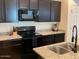 Modern kitchen featuring dark cabinetry, granite countertops, and stainless steel sink at 1718 S 82Nd Way, Mesa, AZ 85209