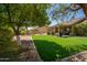 Beautiful backyard showcasing a covered patio, lush landscaping, and a well-maintained artificial grass lawn at 18823 N 97Th Ln, Peoria, AZ 85382