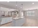Bright kitchen with an island, stainless steel sink, modern pendant lighting and tan-colored tile floors at 18868 E Canary Way, Queen Creek, AZ 85142