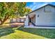 Beautiful curb appeal, featuring a lawn, mature trees, manicured garden beds, gray paint, and inviting front entryway at 20042 W Dunlap Rd, Buckeye, AZ 85326