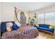 Bright bedroom featuring a colorful owl tapestry, plush bedding, blue sofa, and abundant natural light from the window at 2116 W Marlette Ave, Phoenix, AZ 85015