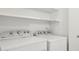 Clean and bright laundry room boasts full-size Whirlpool washer and dryer set; convenient shelving above at 2116 W Marlette Ave, Phoenix, AZ 85015