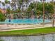 Community pool with beach entry, waterfall features, and ample lounge seating surrounded by lush landscaping at 2218 E Anchor Dr, Gilbert, AZ 85234
