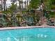 Resort-style community pool with cascading waterfalls and surrounding natural stone landscape for a relaxing environment at 2218 E Anchor Dr, Gilbert, AZ 85234