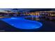 Community pool with an interesting curvy design, covered picnic tables and comfortable lounge chairs at night at 22491 E Mewes Rd, Queen Creek, AZ 85142