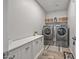Functional laundry room equipped with modern washer and dryer units, storage, and a utility sink at 22491 E Mewes Rd, Queen Creek, AZ 85142