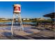 A water tower feature stands on a concrete pad near a lake with picnic tables and benches at 22491 E Mewes Rd, Queen Creek, AZ 85142