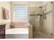 Bathroom featuring a glass block window, soaking tub, and glass enclosed shower at 4834 E Robin Ln, Phoenix, AZ 85054