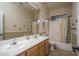 Well-lit bathroom with a double sink vanity, tiled floors, and a shower-tub combo with curtain at 6172 W Kerry Ln, Glendale, AZ 85308