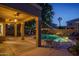 Outdoor patio area at dusk, featuring a covered patio with a pool including a rock waterfall and string lights at 6172 W Kerry Ln, Glendale, AZ 85308
