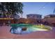 Backyard pool with rock features, lounge area, and privacy fence illuminated by warm string lights at twilight at 6172 W Kerry Ln, Glendale, AZ 85308