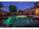 Backyard pool with rock features, outdoor furniture, and lush greenery, enhanced by warm lighting for evening ambiance at 6172 W Kerry Ln, Glendale, AZ 85308