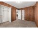 Bedroom with knotty pine paneling, carpet, a closet, and a view of bathroom at 7126 N 29Th Dr, Phoenix, AZ 85051