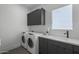Functional laundry room with modern appliances, built-in cabinets, and a sink at 8520 E Cactus Wren Rd, Scottsdale, AZ 85250