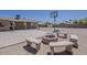 Backyard sitting area features a fire pit surrounded by concrete benches, basketball court, and covered patio at 10655 E Broadway Rd, Mesa, AZ 85208