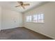 Simple bedroom with neutral carpet, white walls, ceiling fan, and two windows at 10655 E Broadway Rd, Mesa, AZ 85208