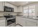 Bright kitchen with stainless steel appliances, white cabinets, and modern tile flooring at 10655 E Broadway Rd, Mesa, AZ 85208