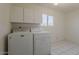 Bright laundry room features a Maytag washer and dryer, white cabinets, and tile flooring near a sunny window at 10655 E Broadway Rd, Mesa, AZ 85208
