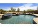 Resort-style pool and spa with waterfall feature, surrounded by lush landscaping and desert views at 1141 W Stephanie Ln, San Tan Valley, AZ 85143