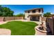 Large backyard with artificial grass, block fence, patio, and decorative water fountain at 11841 W Laurel Ln, El Mirage, AZ 85335