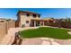 A spacious backyard features manicured artificial turf, a covered patio, and a charming fountain at 11841 W Laurel Ln, El Mirage, AZ 85335