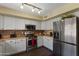 Modern kitchen featuring white cabinets, stainless steel appliances, and an exposed brick backsplash at 12814 W Edgemont Ave, Avondale, AZ 85392