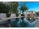 Sparkling swimming pool with stone fireplace and lush landscaping creating a serene backyard at 13131 N 153Rd Ave, Surprise, AZ 85379
